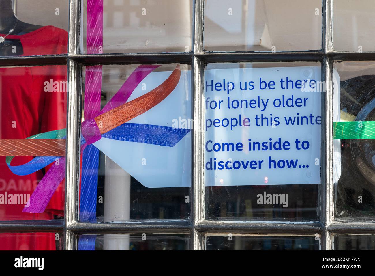 Melden Sie sich im Age UK Charity Shop „Helfen Sie uns, diesen Winter für einsame ältere Menschen da zu sein. Komm rein und entdecke, wie...“, England, Großbritannien, November 2022 Stockfoto