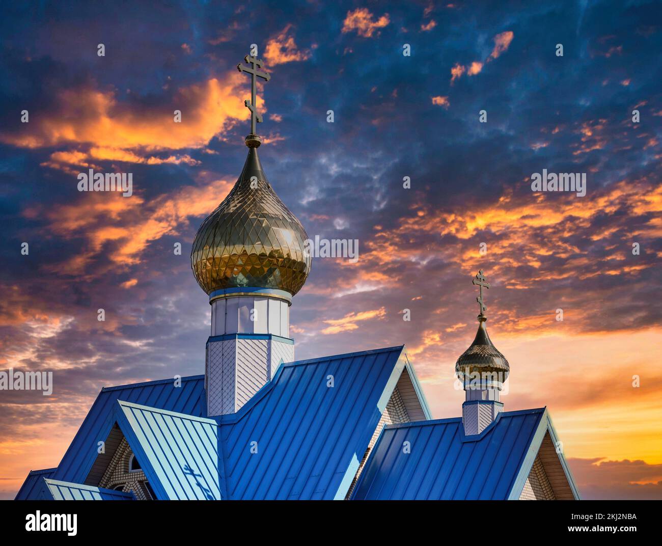 Ein Teilblick auf die orthodoxe Kirche unter dem dramatischen dunklen bewölkten Himmel bei Sonnenuntergang Stockfoto