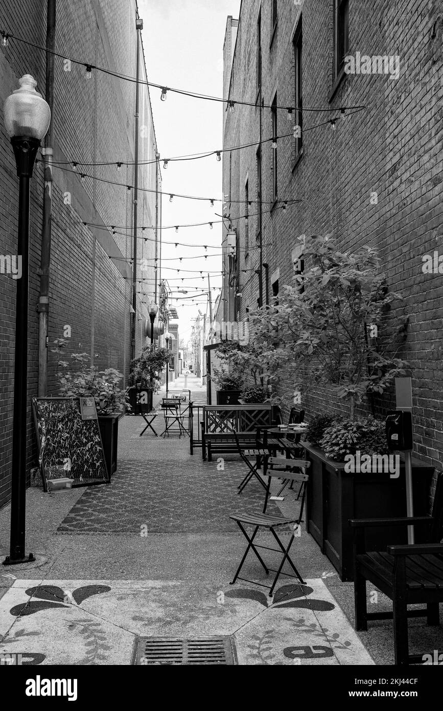 Ein kleines Café im Freien in einer Gasse mit Lichterketten zwischen Ziegelgebäuden Stockfoto