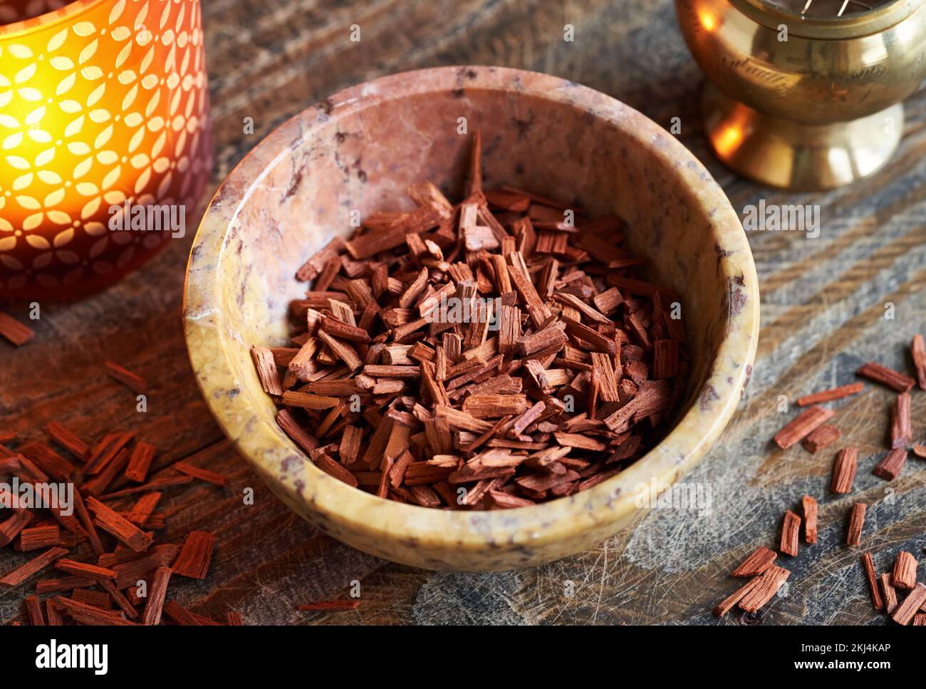 Rote Sandalenholzstücke in einer Schüssel, mit einer Aromalampe und einem Räucherbrenner im Hintergrund Stockfoto