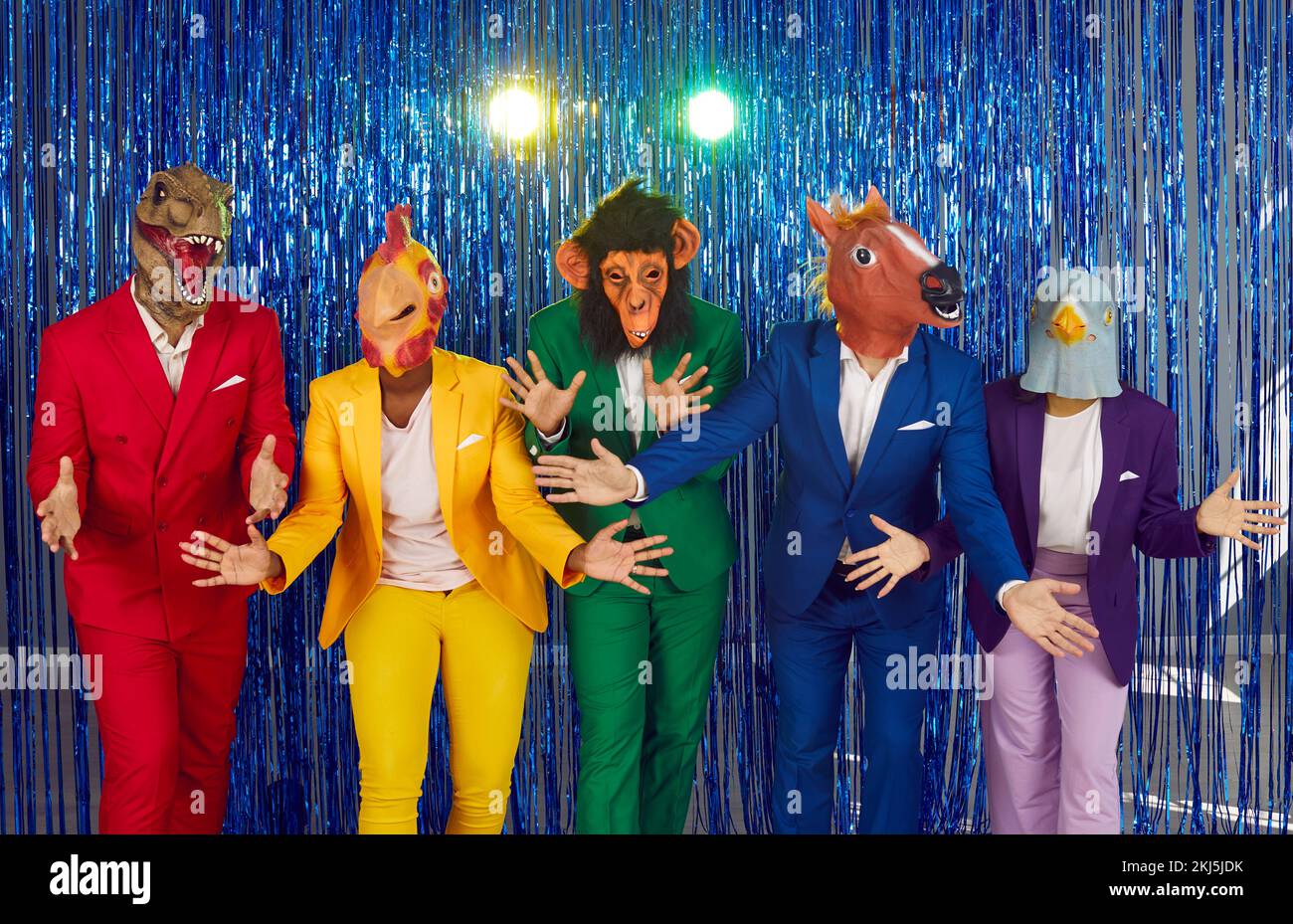 Menschen mit lustigen Masken von Köpfen verschiedener Tiere tanzen auf einer Disco-Party auf glänzendem Hintergrund. Stockfoto