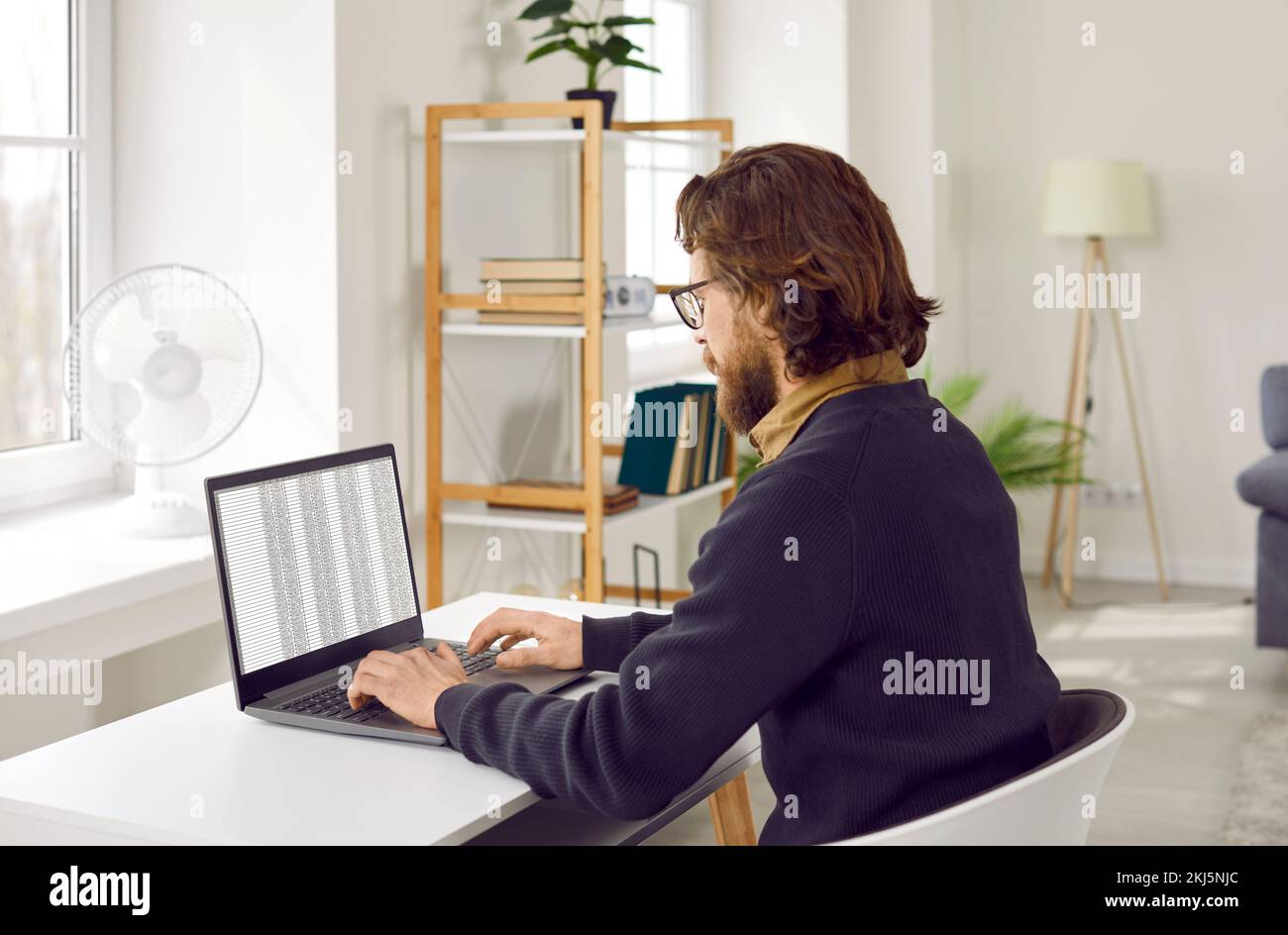 Geschäftsmann, der sich auf die Arbeit an einem Projekt konzentriert und mit einem digitalen Programm auf einem Notebook arbeitet. Stockfoto