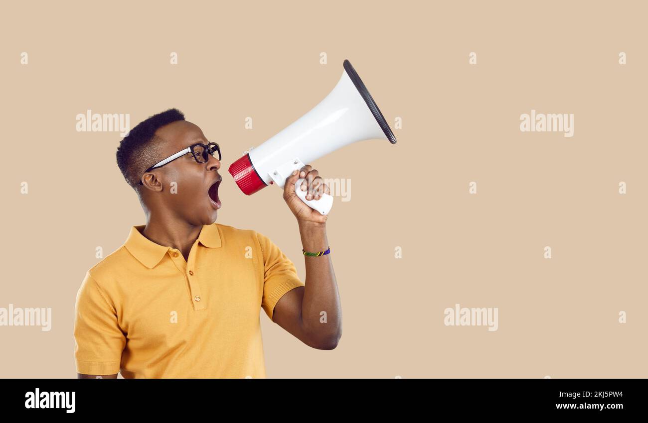afroamerikanischer Mann mit Lautsprecher, der laute Werbung auf hellbeigem Hintergrund macht. Stockfoto