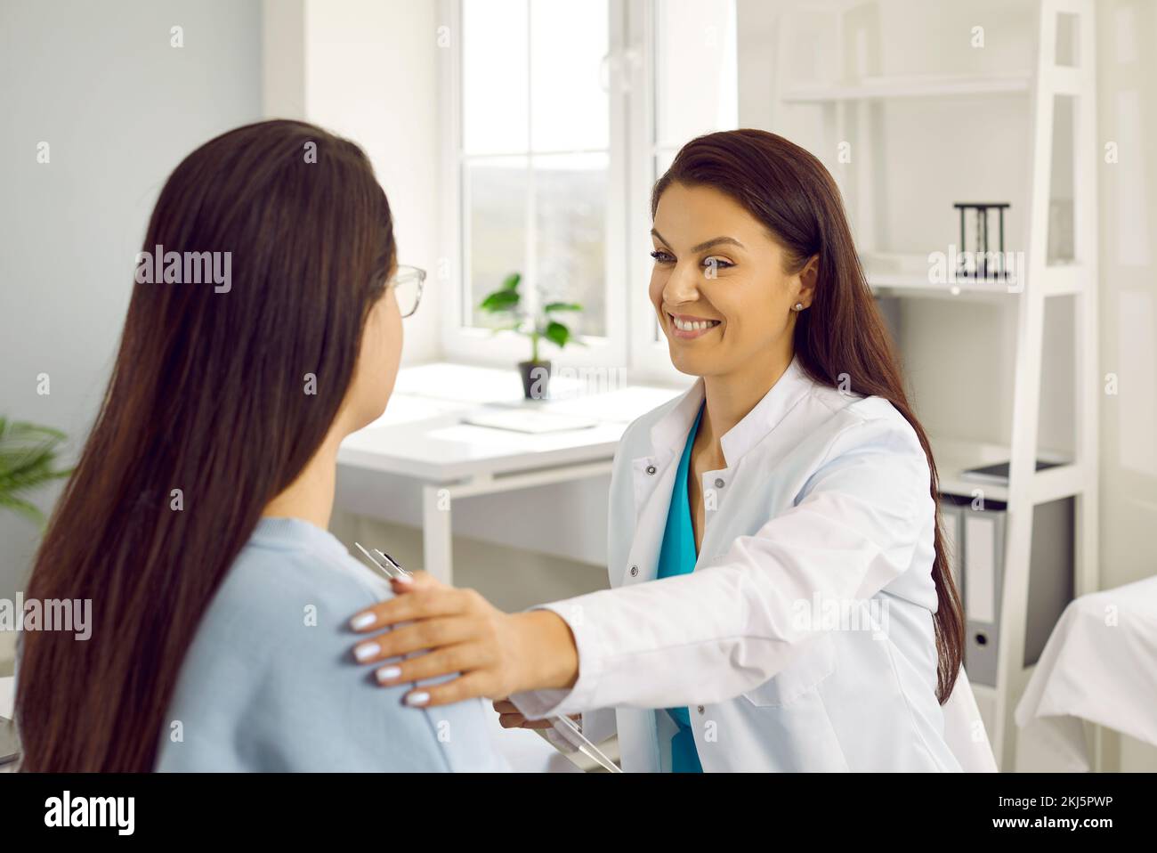 Freundliche Ärztin, die mit einer Patientin spricht, die sie während des Empfangs unterstützt und tröstet. Stockfoto
