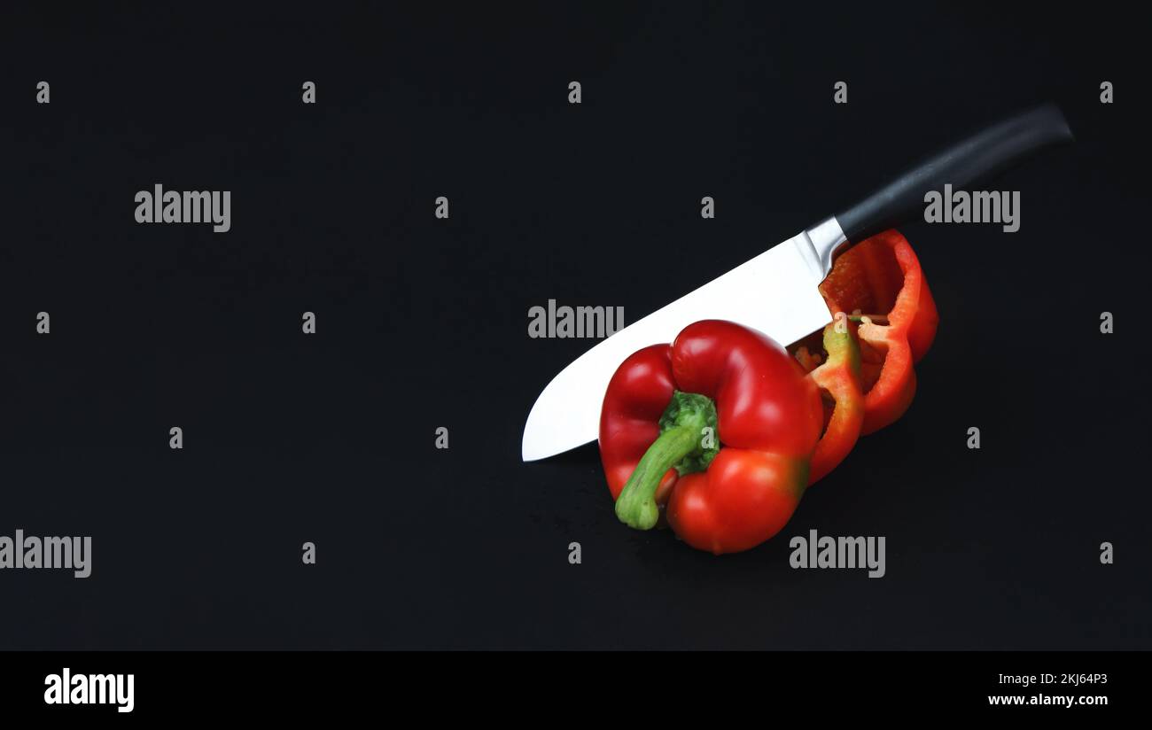 Pfeffer und Küchenmesser auf dunklem Hintergrund. Gehackter Pfeffer und Messer Stockfoto