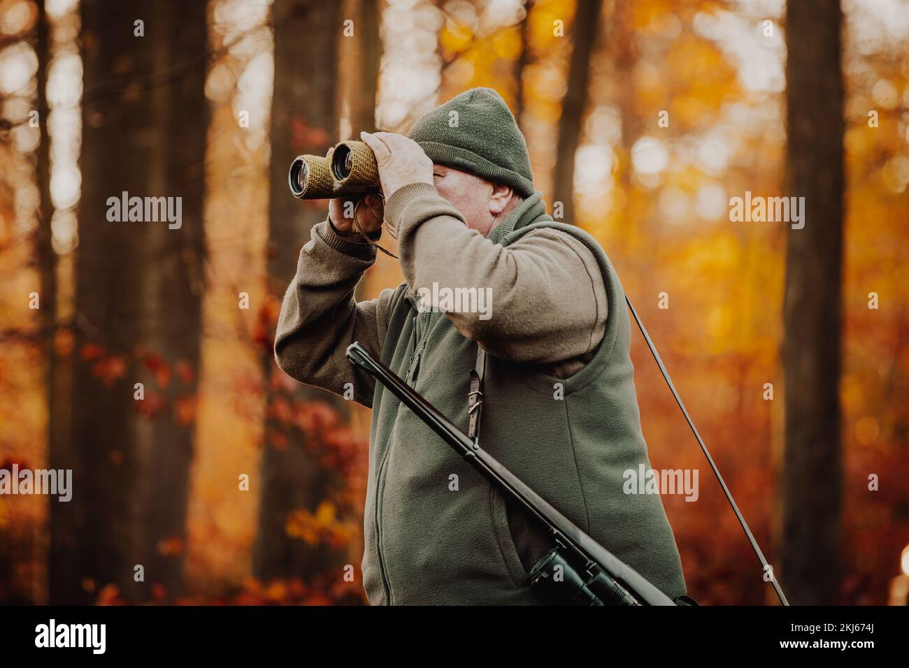 Jäger oder Ranger mit Teleskop auf der Suche nach wilden Tieren im Wald, Jagdzeit, Herbstsaison, Jagd- und Menschenkonzept Stockfoto