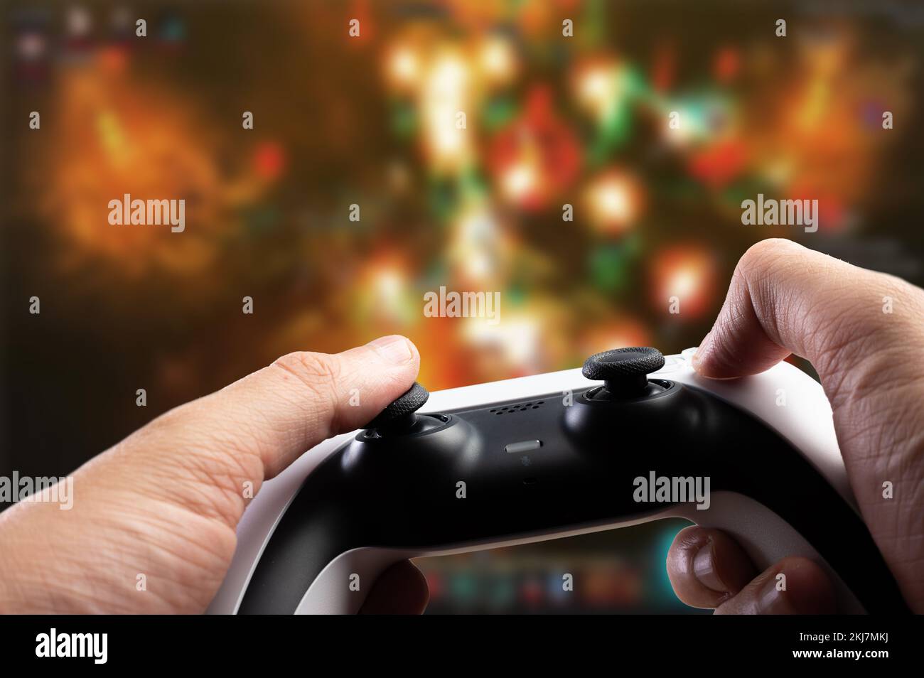 Moderner Joystick in den Händen eines Spielers mit fantasiellem Hintergrund. Videospiele, neue drahtlose Technologien, virtuelle Realität, Kommunikation mit Freunden. Stockfoto