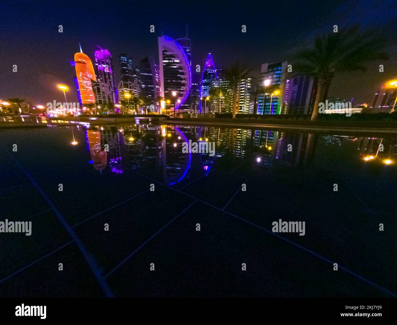 Nachtszene der Skyline von Doha in Katar. Die malerische Stadtlandschaft von West Bay bei Nacht spiegelt sich im Downtown Park wider. Naher Osten, Arabische Halbinsel in Persisch Stockfoto