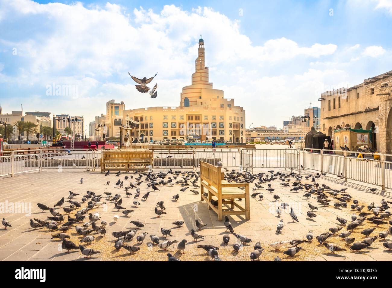 Doha, Katar - 20. Februar 2019: Viele Tauben fliegen im Souk Waqif vor dem Fanar Islamic Cultural Center mit Moschee und Minarett im Hintergrund Stockfoto