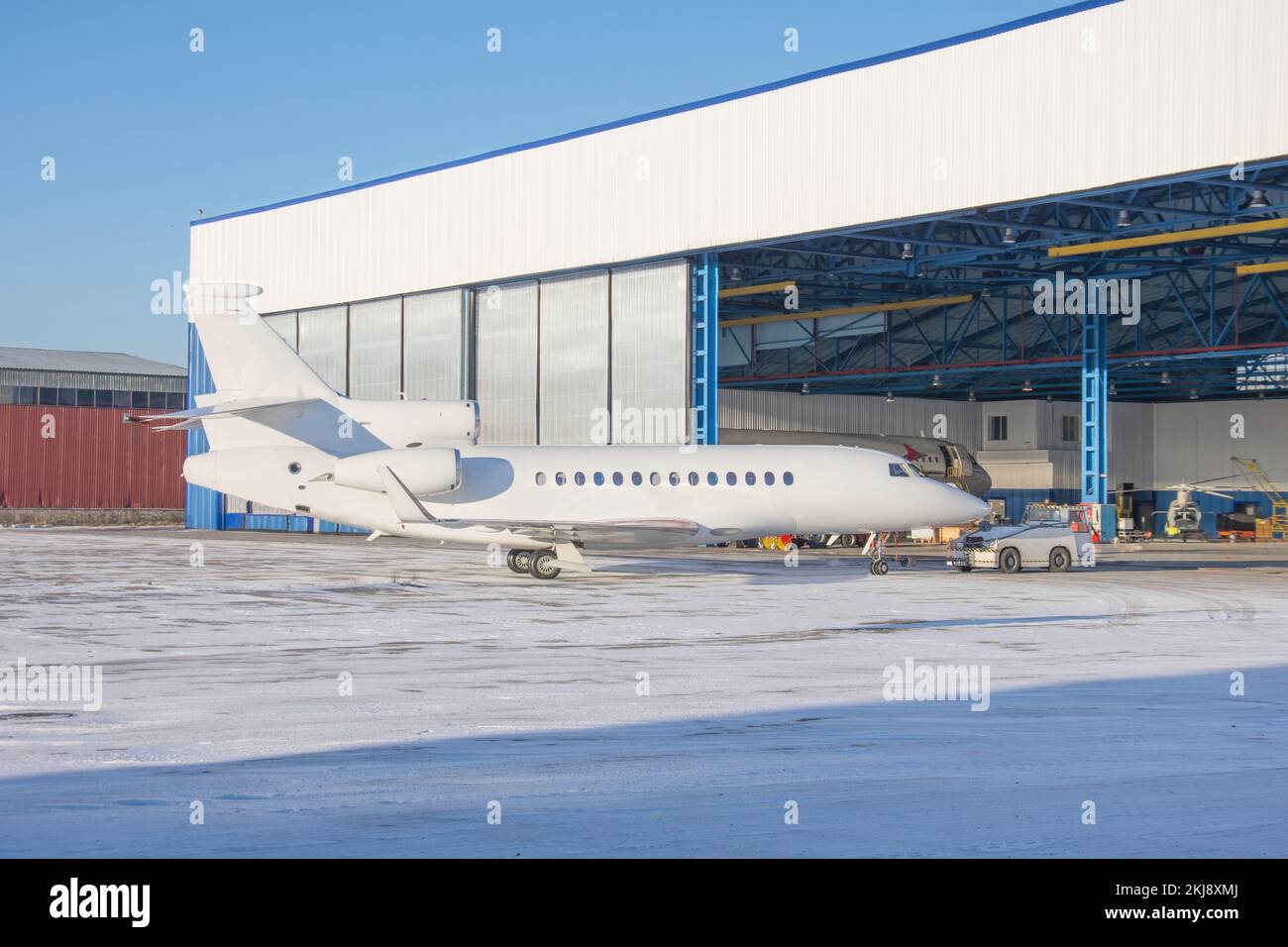 Das Flugzeug wird im Inneren des Flugzeughangars zur Wartung mit einem Schlepper geliefert Stockfoto