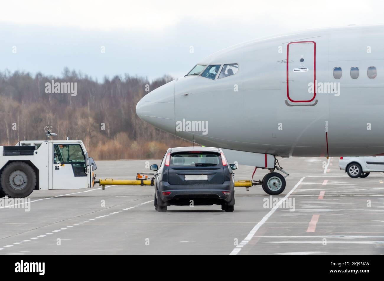 Schlepperflugzeug zurückschieben. Flugplatzservice im Auto wartet darauf, das Flugzeug an der Kreuzung zu verpassen Stockfoto