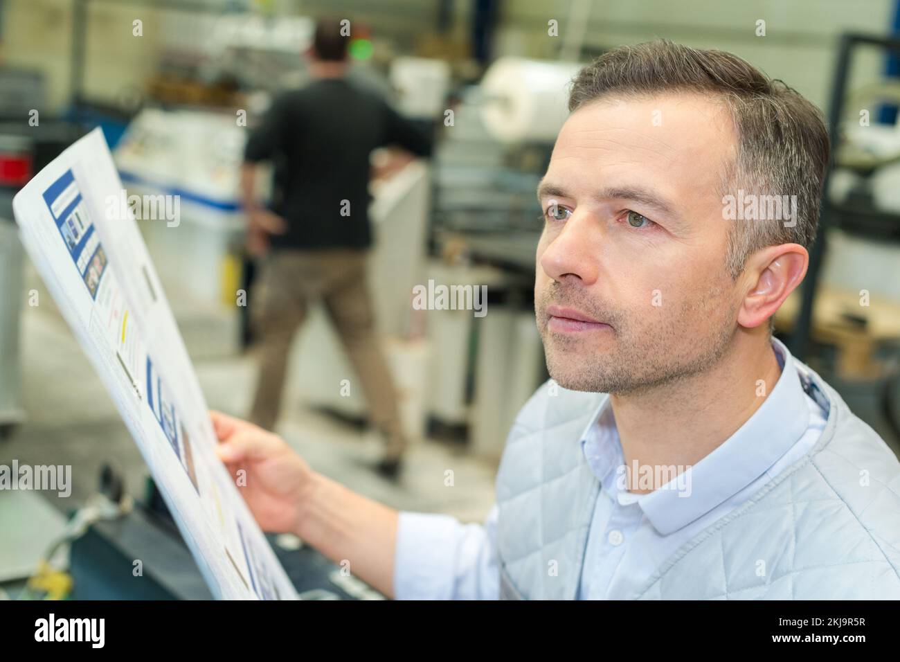 Mitarbeiter, der ein Dokument in einem Druck- und Druckzentrum überprüft Stockfoto