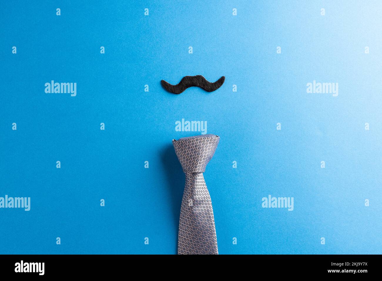 Komposition von falschem Schnurrbart und Krawatte auf blauem Hintergrund mit Kopierraum Stockfoto