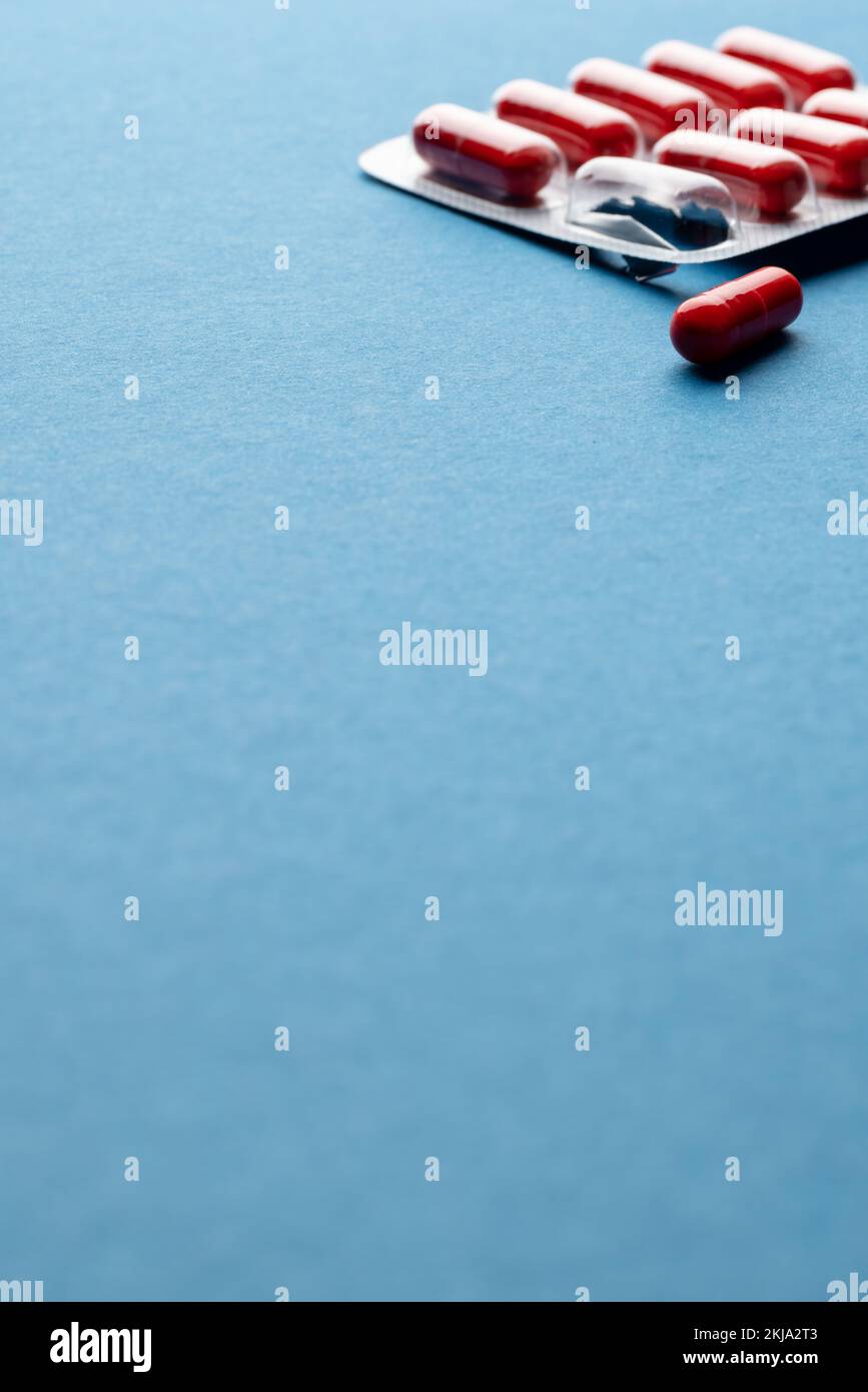 Vertikal von roten Pillen in Blisterpackung und eine Pille aus, auf blauem Hintergrund mit Kopierbereich Stockfoto
