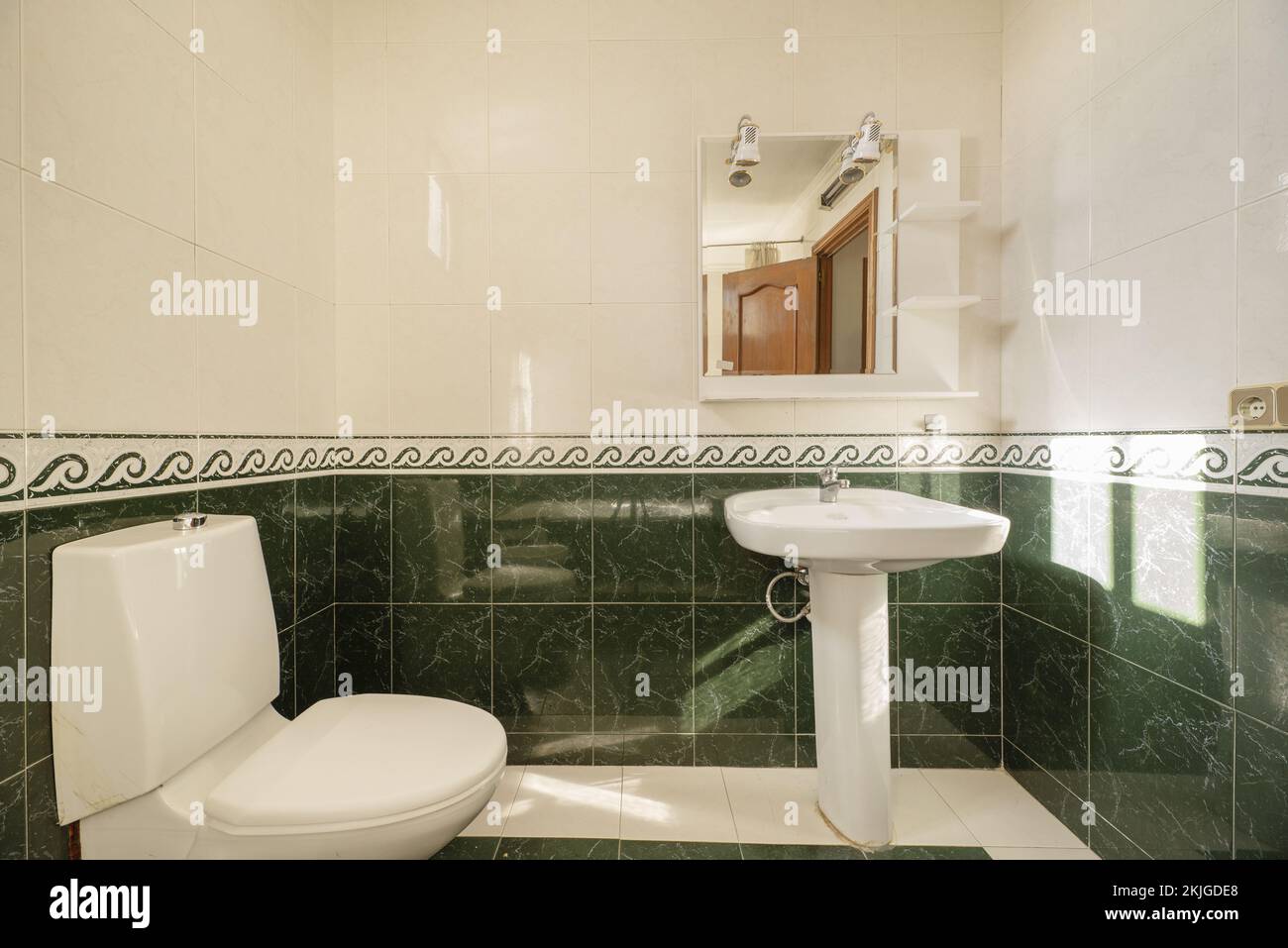 Grün gefliestes Badezimmer mit eingelegtem Wandspiegel und weißem Porzellanwaschbecken Stockfoto