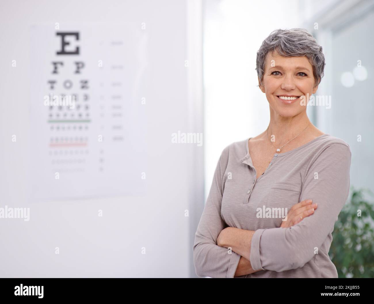 Pass gut auf deine Augen auf. Porträt einer Optikerin, die neben einem Augentestposter steht. Stockfoto
