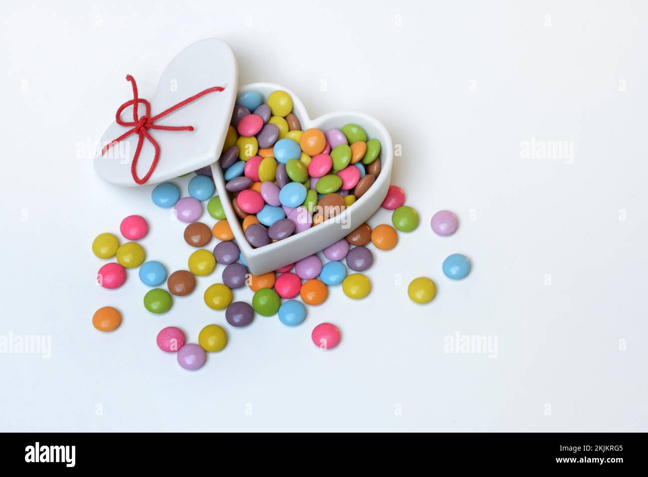 Schokoladenlinsen in herzförmigem Behälter, Smartie Stockfoto