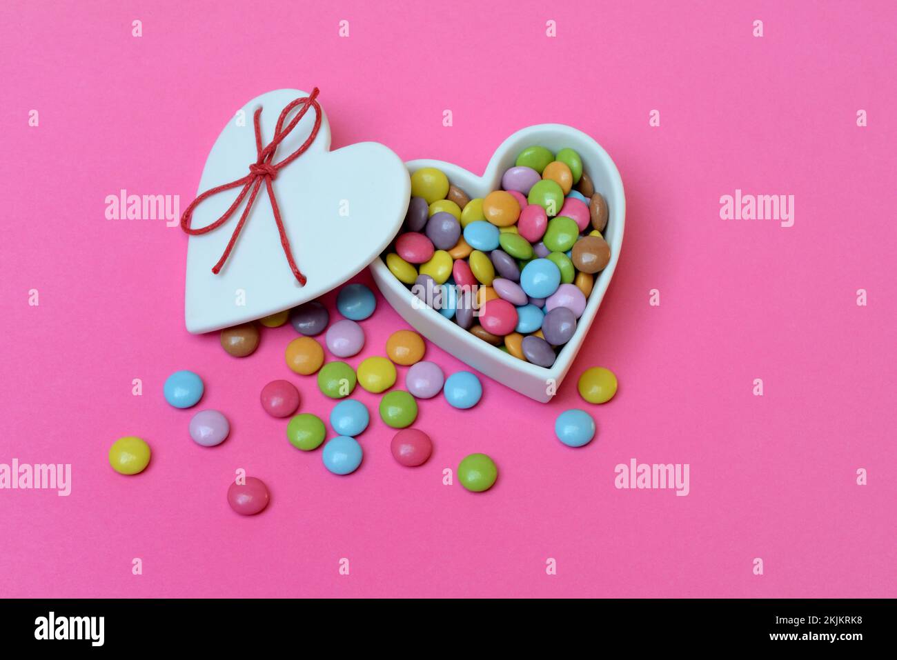 Schokoladenlinsen in herzförmigem Behälter, Smartie Stockfoto