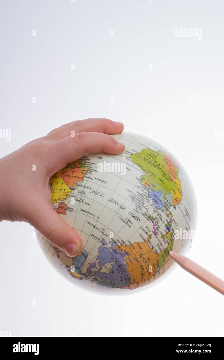 Kind hält einen Globus und einen Stift in auf weißem Hintergrund Stockfoto