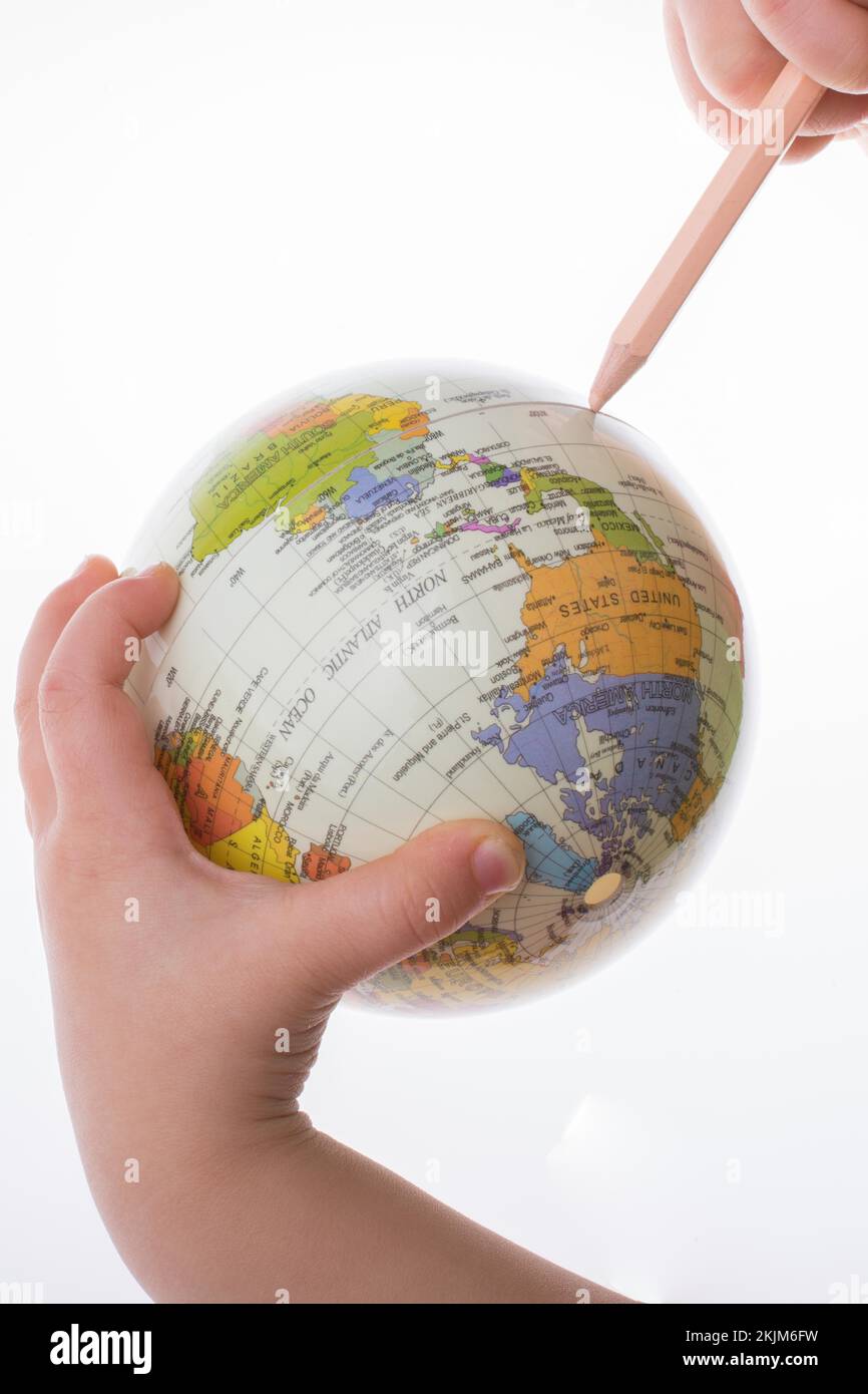 Kind hält einen Globus und einen Stift in auf weißem Hintergrund Stockfoto