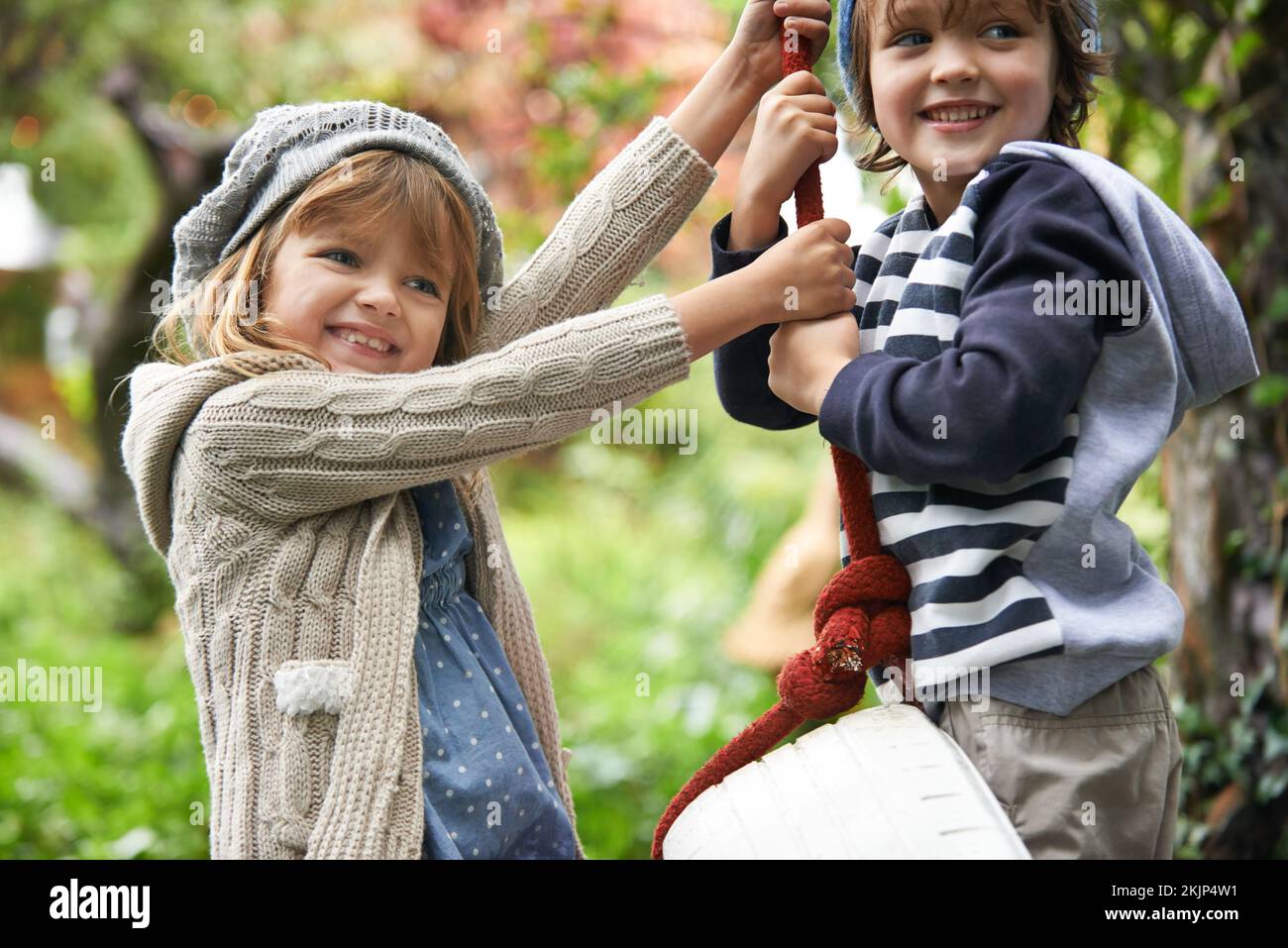 Spaß auf der Schaukel. Zwei süße Kinder, die auf einer Reifenschaukel in ihrem Garten spielen. Stockfoto