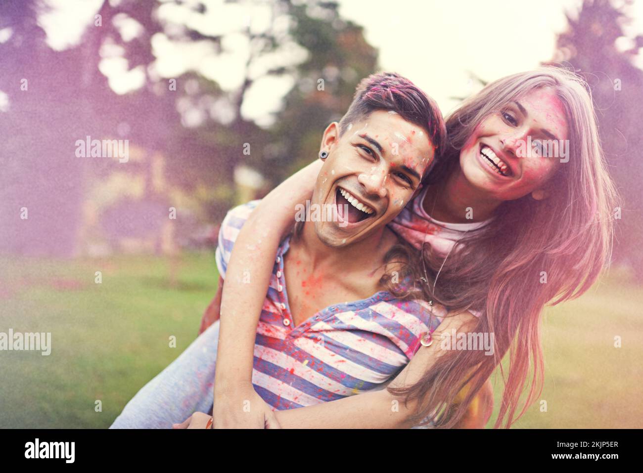 Alles ist besser in Farbe. Ein junger Mann, der seine Freundin auf einem Farbfestival quält. Stockfoto