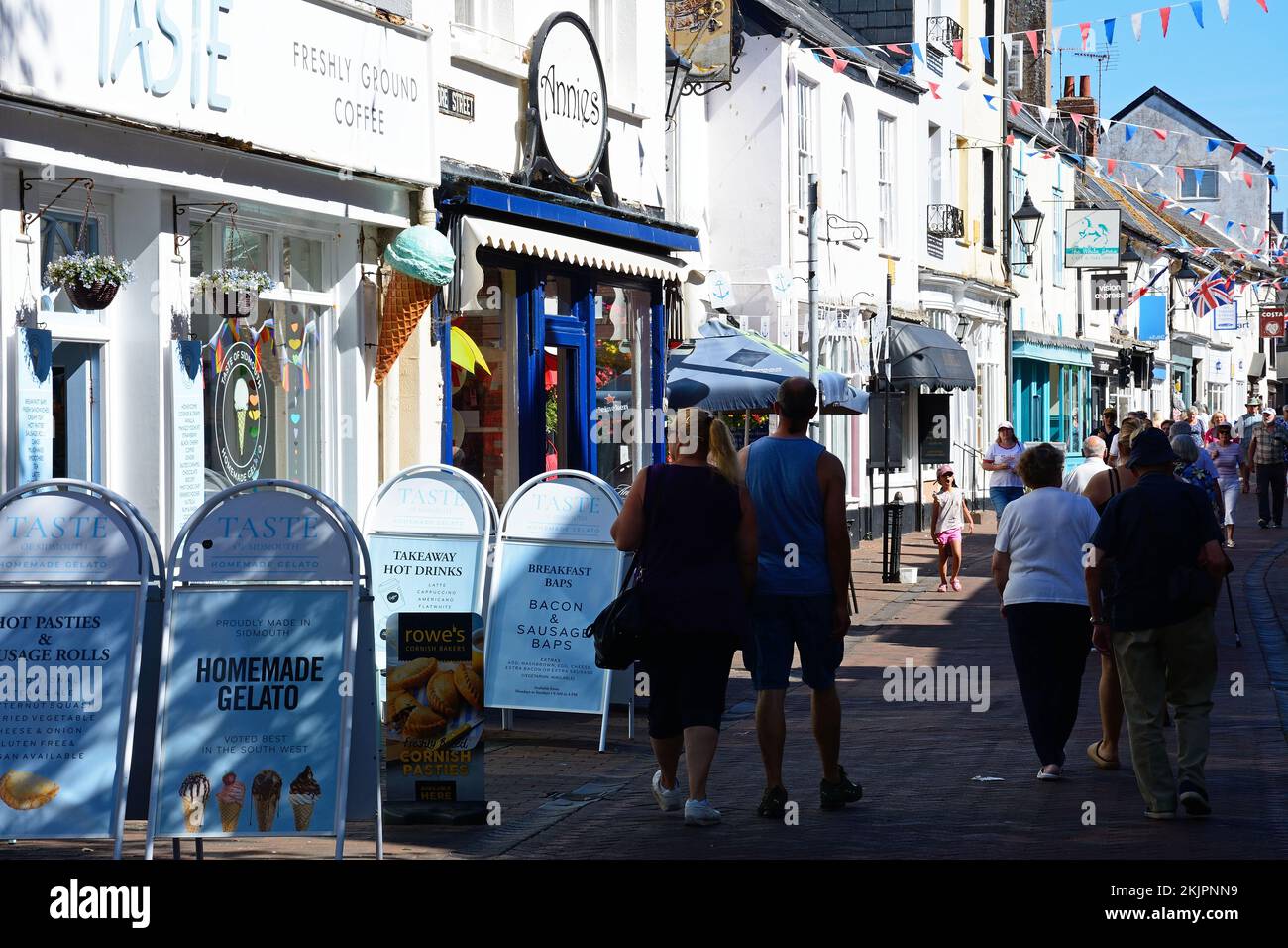 Blick auf Shoppers und Shops entlang der Old Fore Street im Stadtzentrum, Sidmouth, Devon, Großbritannien, Europa. Stockfoto