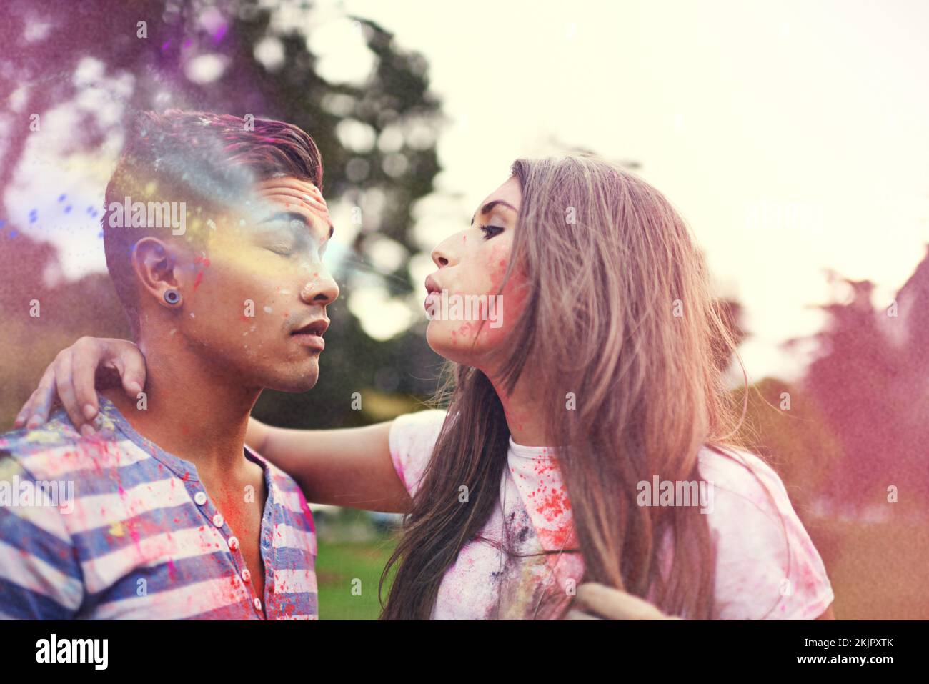 Bunte Küsse blasen. Eine junge Frau, die ihren Freunden kräftige Farbe aus den Augen bläst. Stockfoto