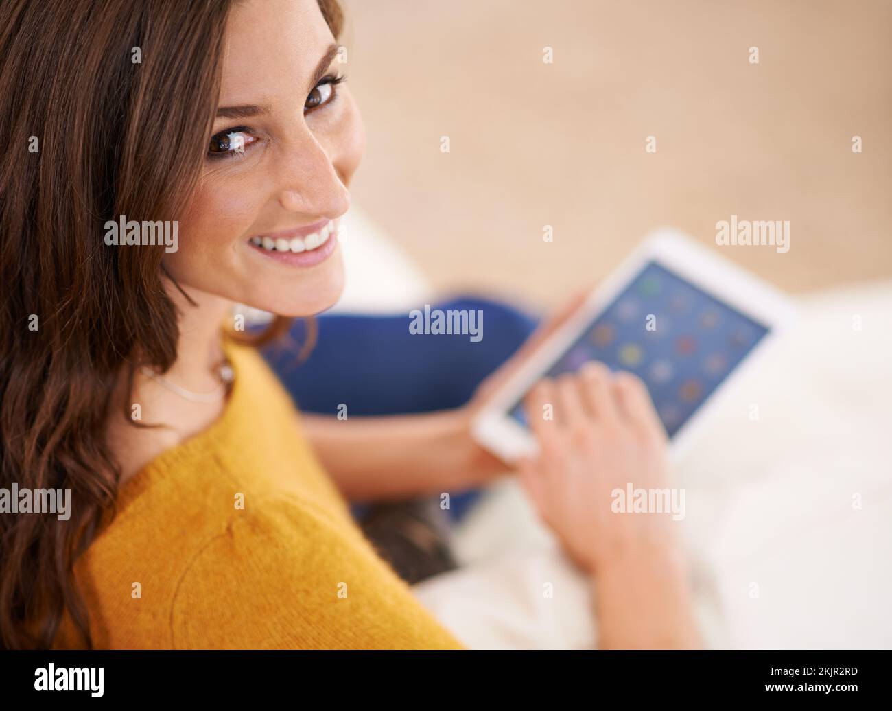 Zeit, ein paar Freunde zu treffen. Eine wunderschöne junge Frau, die ein digitales Tablet im Innenbereich benutzt. Stockfoto