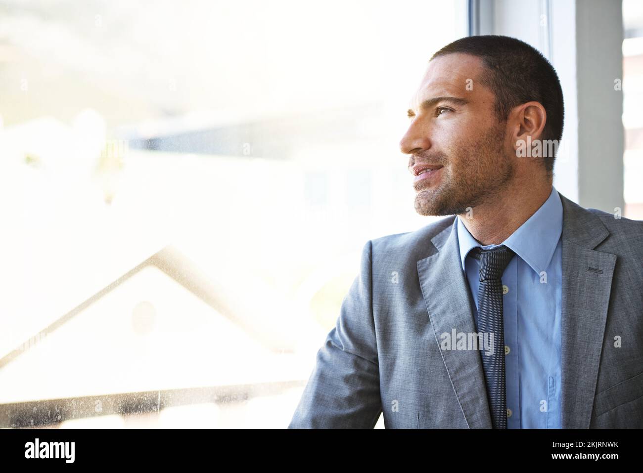 Er hat eine Vision für seine Zukunft. Ein gutaussehender Geschäftsmann, der aus seinem Bürofenster schaut. Stockfoto