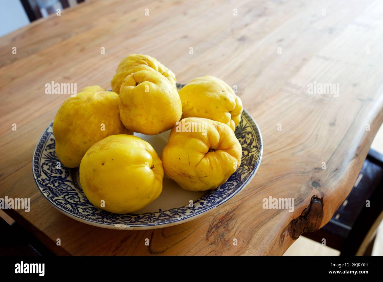 Quitten in einer Porzellanplatte auf einem Holztisch. Stockfoto