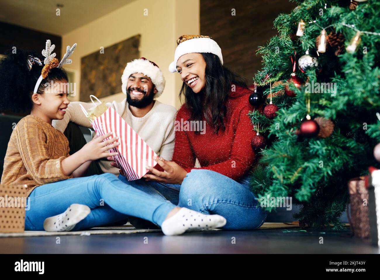 Familie, weihnachtsfeier und Geschenke, glückliches Lächeln und Liebe auf dem Boden zu Hause, Festtag und Überraschung, Mädchen, Mutter und Vater feiern Stockfoto