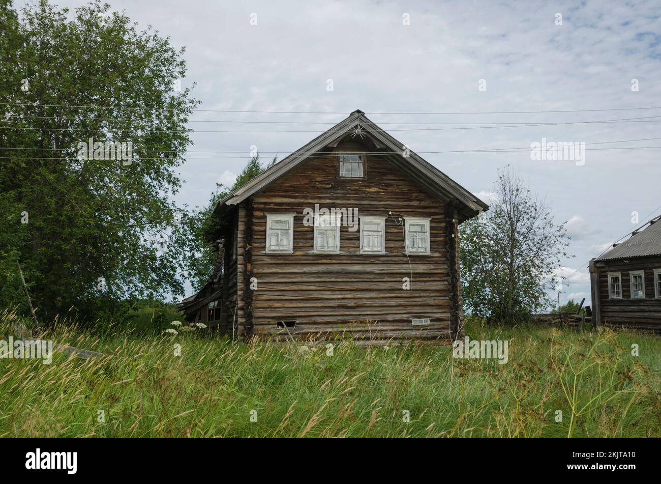 Verlassene Holzhäuser im russischen Dorf. Grasstraße Stockfoto