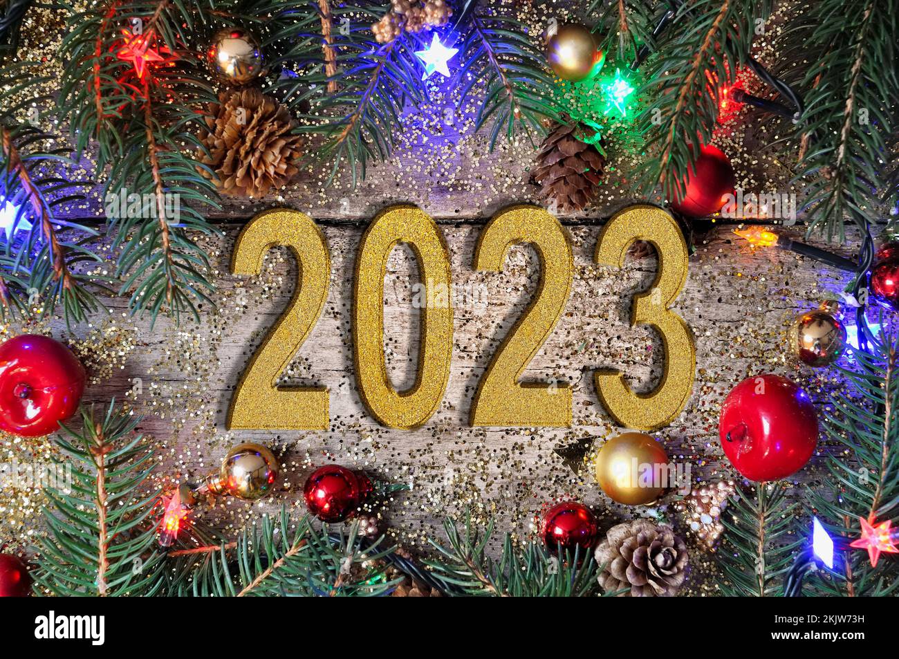 Silvester 2023 mit goldener Zahl auf einer Planke mit Weihnachtsschmuck und Lichtern Stockfoto