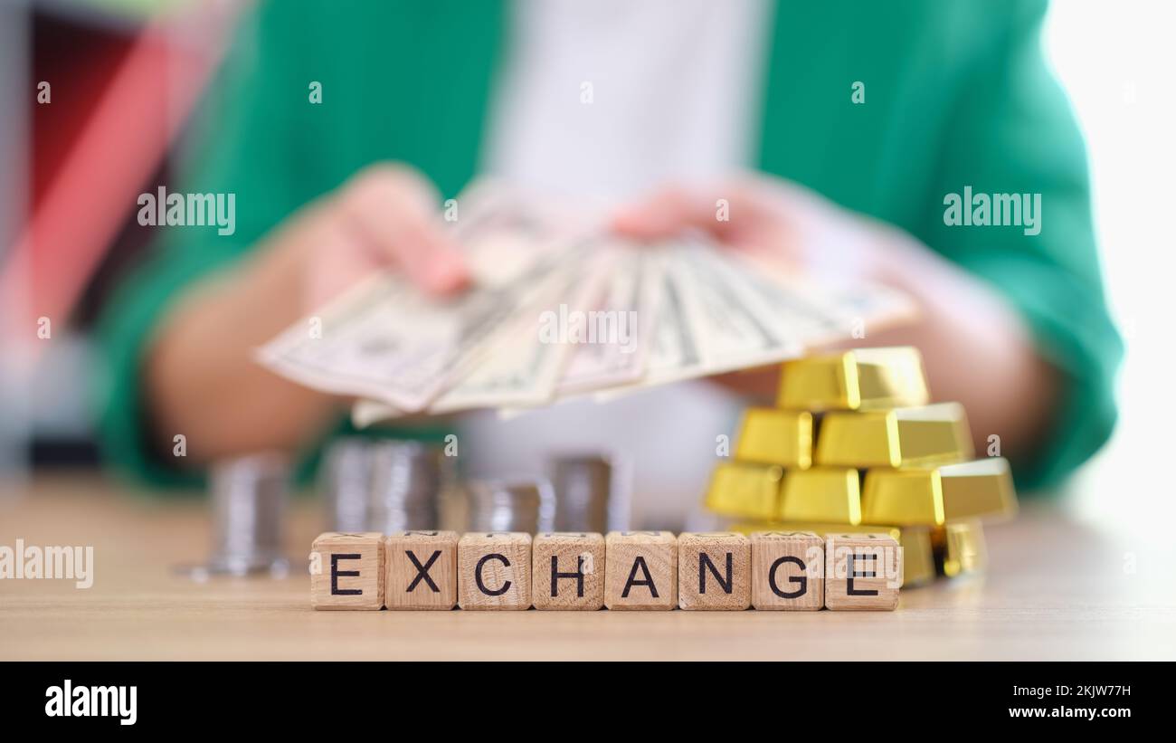 Frau mit Banknoten, Bargeld und Goldbarren, Münzen auf dem Tisch Stockfoto