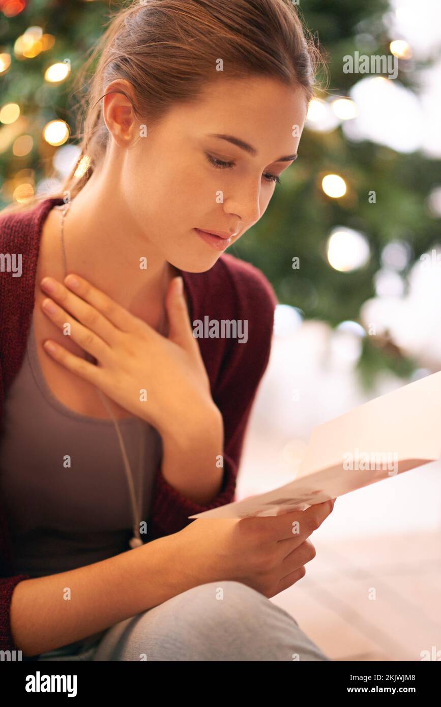 Junge Frau liest weihnachtskarte, Brief und emotionale Notiz im Wohnzimmer während Winterfeier, Ferien und Ferien. Weiblich, festlich Stockfoto