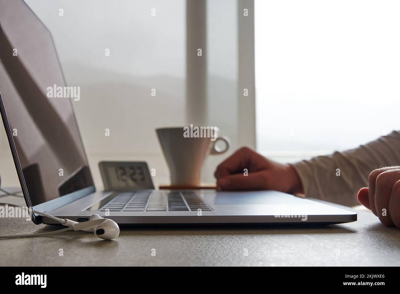 Mann, der von zu Hause aus am Schreibtisch arbeitet, mit Laptop und Kaffeebecher. Freiberufler und Geschäftskonzepte Stockfoto