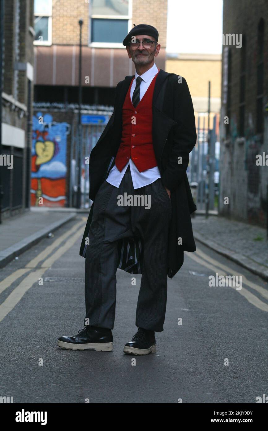 Ein intelligenter, individuell gekleideter Mann mit Baskenmütze, Weste und langem Mantel in London Stockfoto