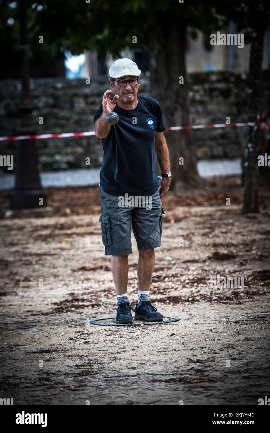 Ein Spieler wirft einen Ball, Boule während eines traditionellen französischen Pétanque-Spiels auf dem Dorfplatz Stockfoto