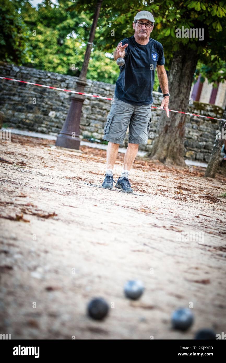 Ein Spieler wirft einen Ball, Boule während eines traditionellen französischen Pétanque-Spiels auf dem Dorfplatz Stockfoto
