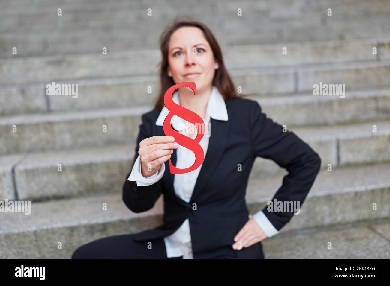 Erfolgreiche Anwältin mit einem großen roten Absatzschild als Gerechtigkeit- und Rechtssymbol Stockfoto