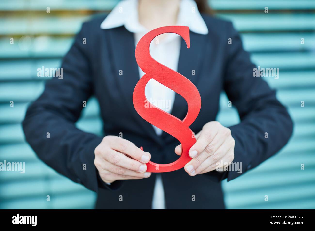 Hände einer Geschäftsfrau, die ein großes rotes Absatzsymbol als Rechtsbegriff hält Stockfoto