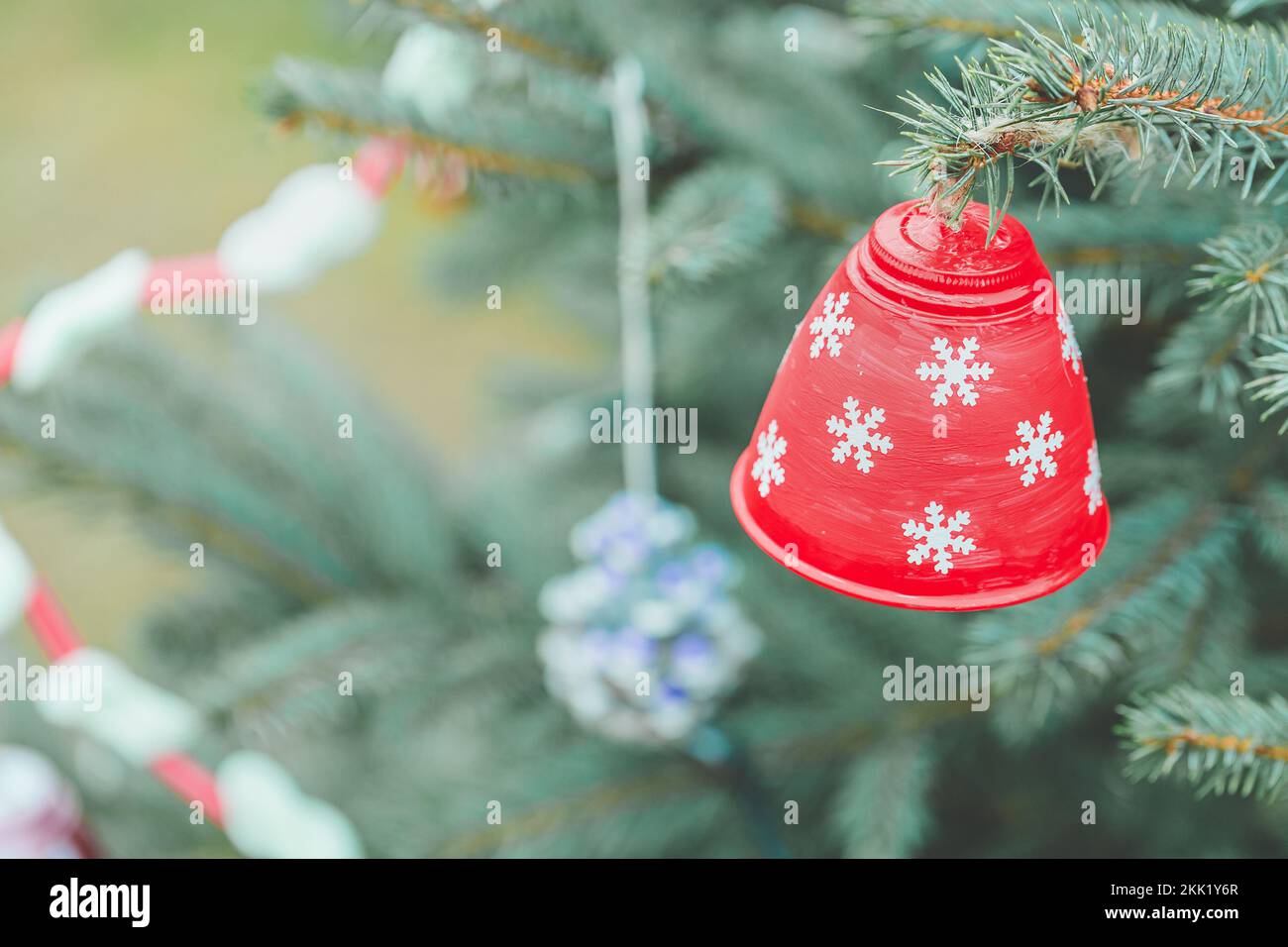 Bemalte, handgemachte Plastikglocke am Weihnachtsbaum. Heimwerkerideen für Kinder. Umwelt-, Recycling-, Upcycling- und Null-Abfall-Konzept. Selektiver Fokus Stockfoto