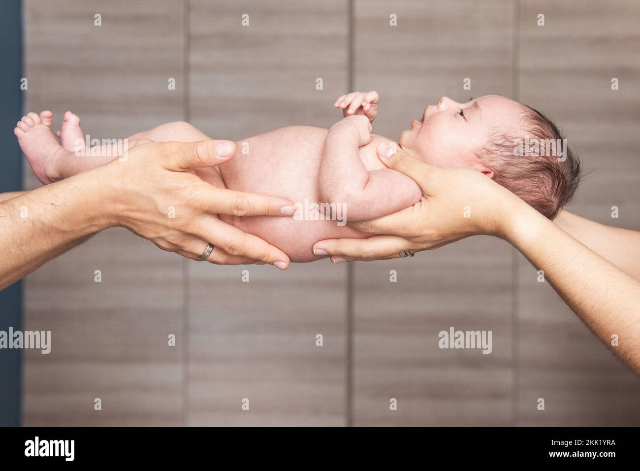 Die Hände einer Mutter und eines Vaters, die ihr Baby halten Stockfoto