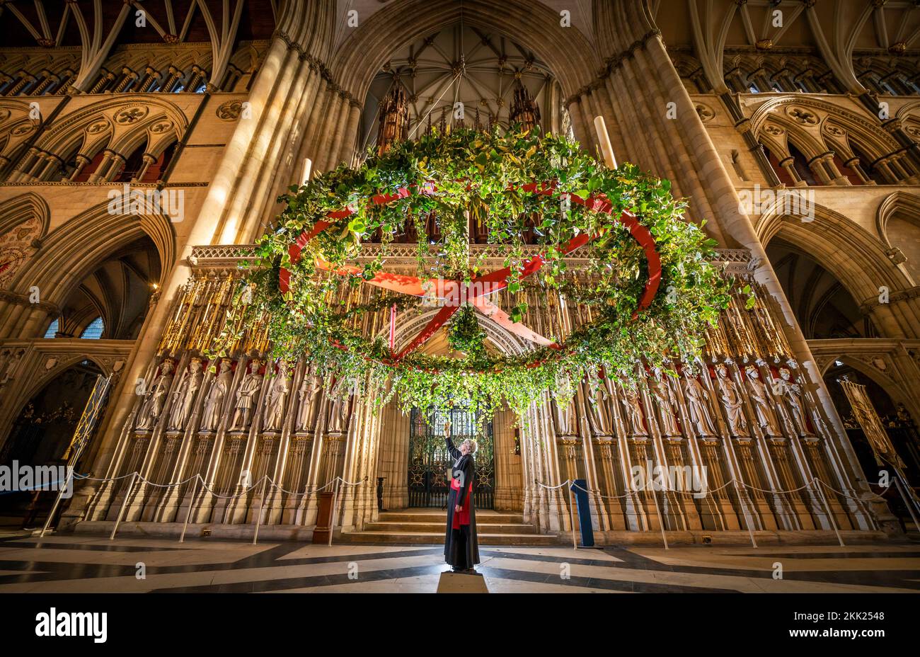 Canon Missioner Maggie McLean beobachtet, wie der Adventskranz auf seine traditionelle Position unter dem Central Tower im York Minster angehoben wird. Foto: Freitag, 25. November 2022. Stockfoto
