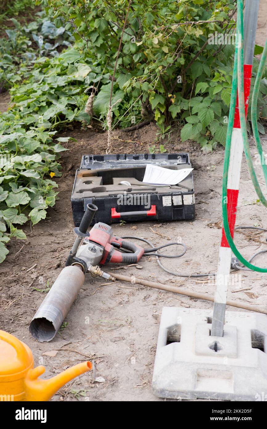 Ein vertikaler Prozess des Austauschs des alten Gartenzauns durch einen neuen mit einer Kernbohrmaschine Stockfoto