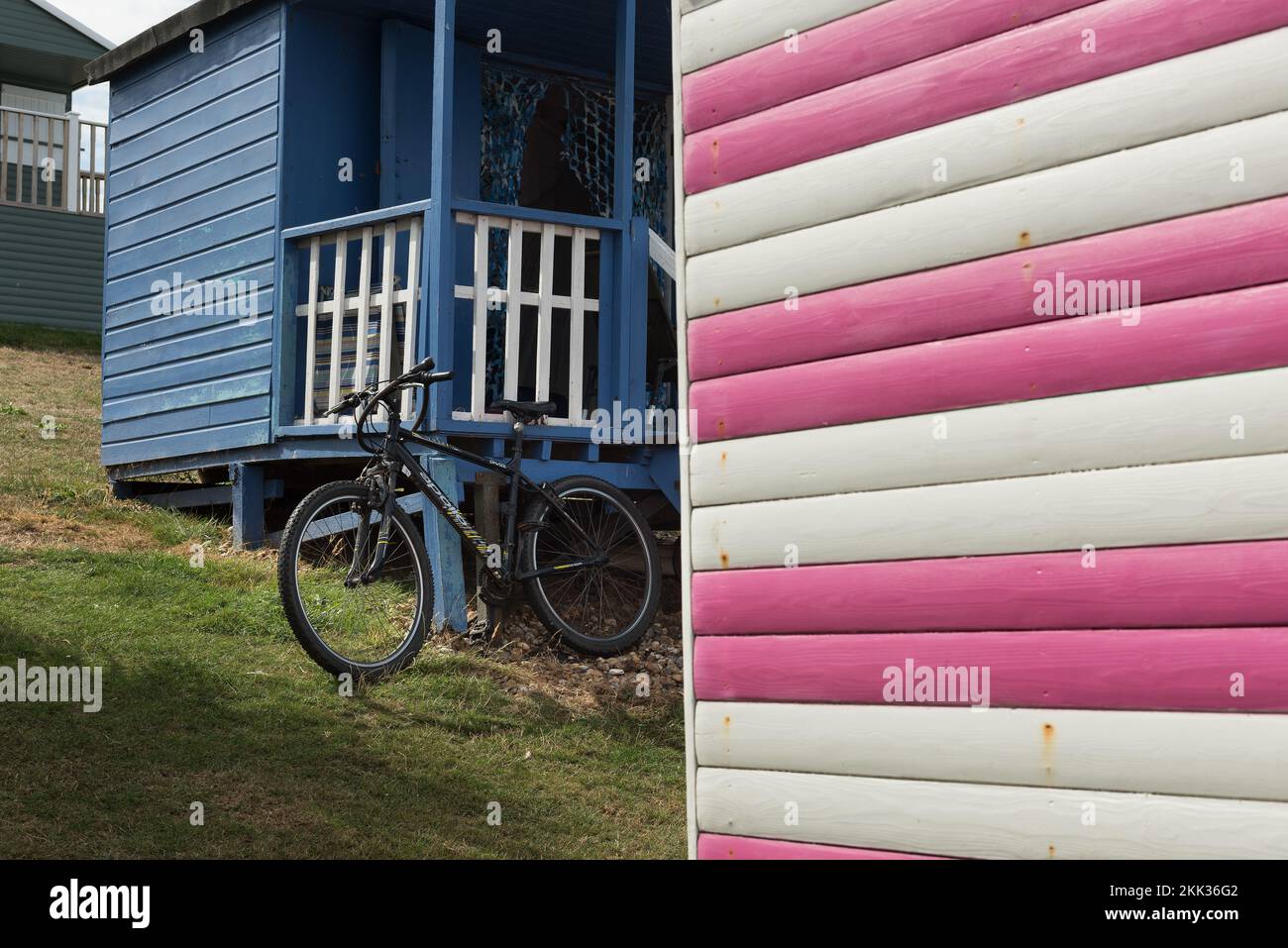 Ein ungesichertes Fahrrad wird gegen eine Veranda zu einer Strandhütte gestellt, die mit einem Riegel am Rahmen befestigt ist Stockfoto