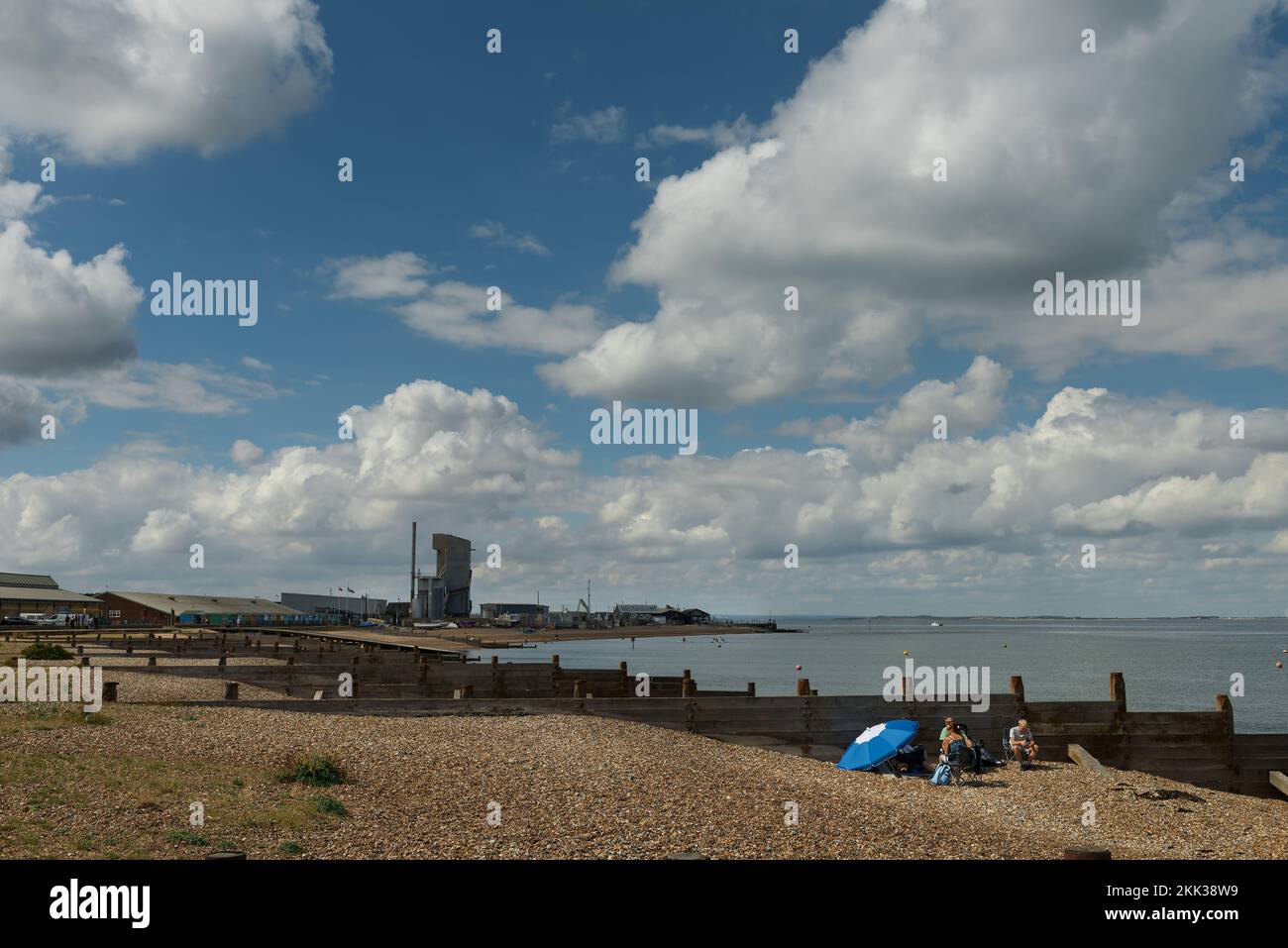 Das Beste aus den Picknickern hinter der Holzgroyne mit Hafen am Meer und Zementarbeiten im Hintergrund in Whitstable Stockfoto