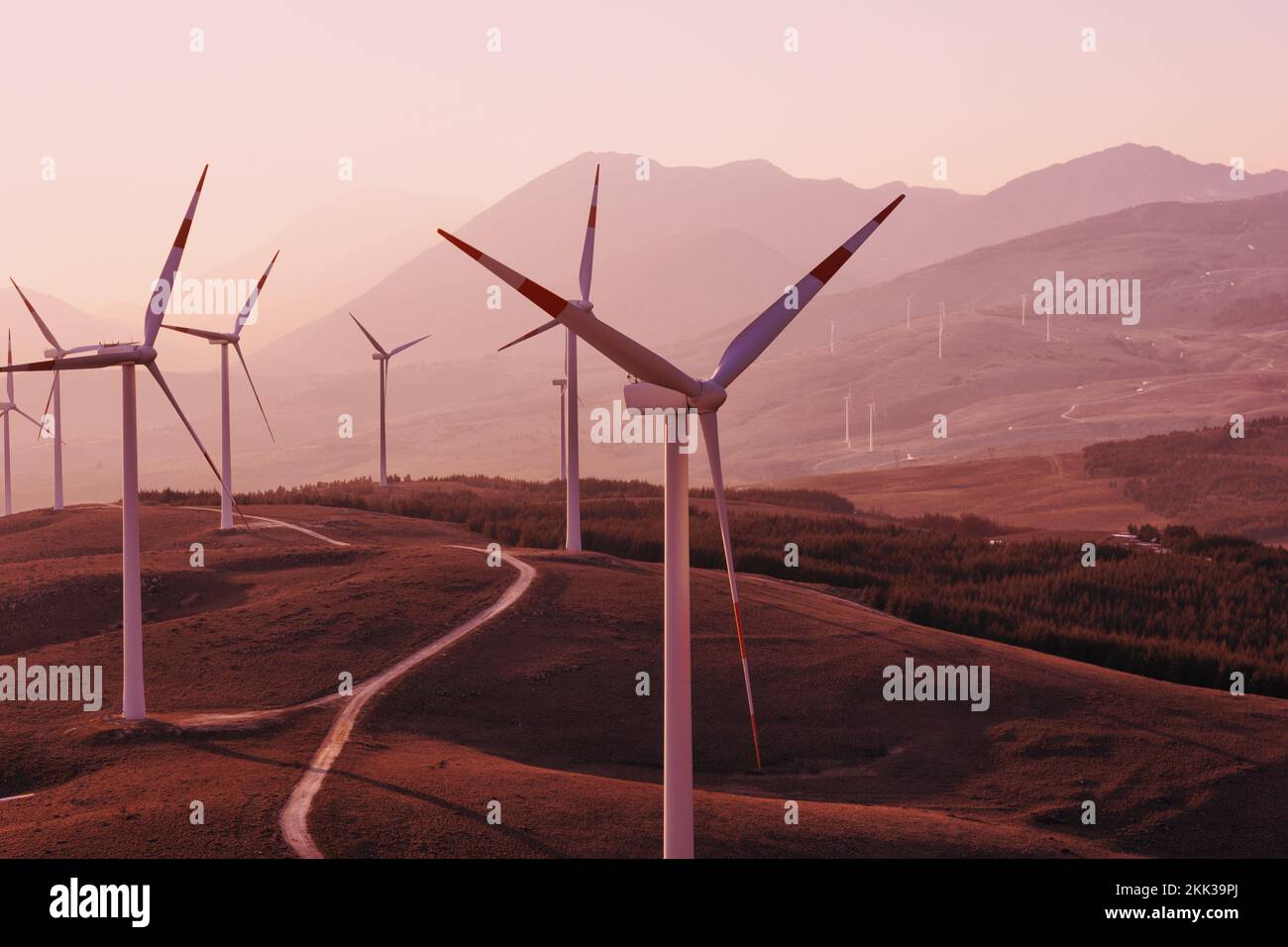 Ein roter Sonnenuntergang aufgrund des Klimawandels und der globalen Erwärmung in den italienischen Bergen mit einem Windpark voller Windturbinen. Die grüne Wirtschaft ist die einzige Stockfoto