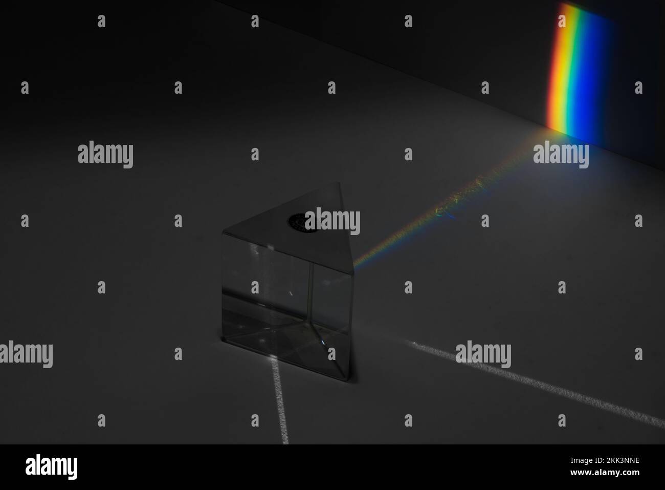 Streuung von weißem Licht in Farben des Spektrums bei unterschiedlichen Wellenlängen mit unterschiedlicher Geschwindigkeit in Glasprisma, das auf die Folie projiziert wird Stockfoto